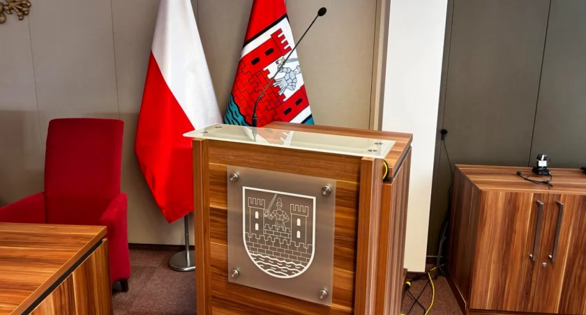 Zdjęcie mównicy i flagi Polski i Sochaczewa w sali konferencyjnej UM Sochaczew