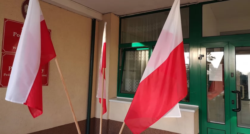Zdjęcie przedstawia flagi Polski przed lokalem wyborczym 