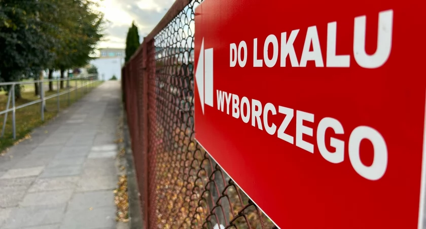 Zdjęcie przedstawia tablicy kierującej do lokalu wyborczego. 