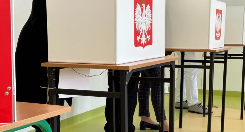 Zdjęcie przedstawia głosujących przy urnach wyborczych 