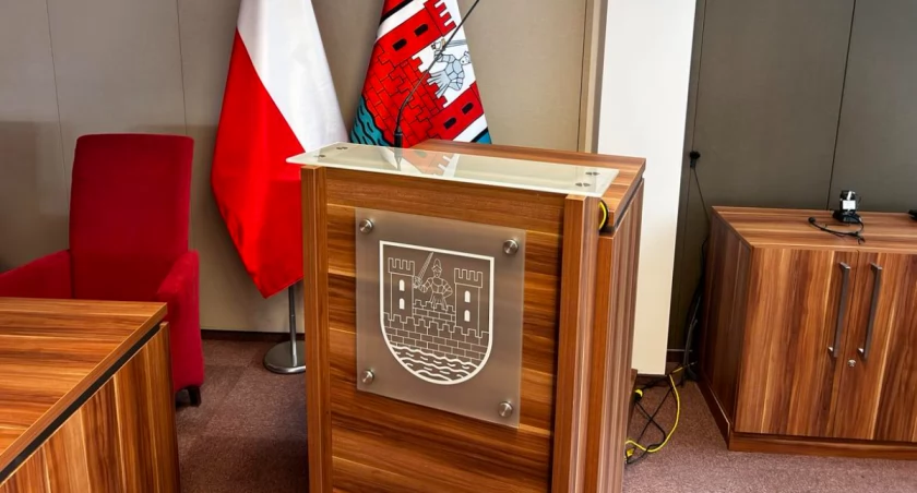 Zdjęcie mównicy w sali konferencyjnej, w tle dwie flaga miasta Sochaczew i Polski. 