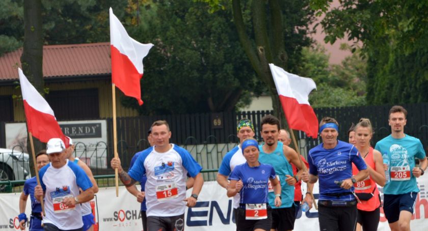 Uczewstnicy sochaczewskiego biegu z flagami państwowymi.